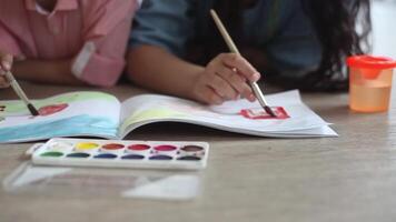 A small handsome boy and a little beautiful girl paint in the album lying on the floor. Close-up. HD video