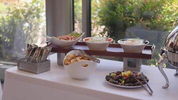 Appetizing Buffet Setup with Various Dishes and Utensils on a White Tablecloth video