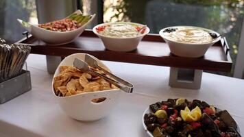 A vibrant assortment of Mediterranean dishes, including dips, stuffed grape leaves, and crispy pita chips, displayed on a buffet table. Perfect for food-themed projects and catering visuals. video