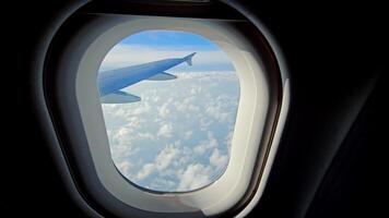 View Through Airplane Window of Wing and Clouds, Perspective from an airplane window showing the wing soaring over soft white clouds video