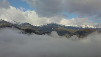 Flying above the clouds in the Carpathian Mountains. The drone is flying high in the blue sky through the fluffy clouds ahead. Beautiful landscape. 4K video