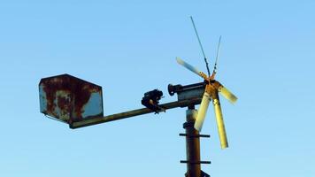 A detailed close-up of an old windmill with rusted blades and tail, set against a clear blue sky. The weathered metal reflects years of exposure to the elements video