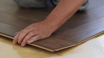 Close-up of a man kneeling and installing laminate flooring in a home. video