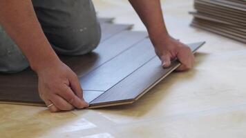 Close-up of a man kneeling and installing laminate flooring in a home. video