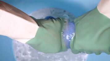 Cleaning involves gloved hands scrubbing with a sponge in soapy water video