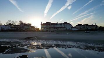 A tranquil beach scene at sunrise with reflecting pools, sandy shoreline, and elegant beachfront houses. Perfect for nature, travel, and residential projects video
