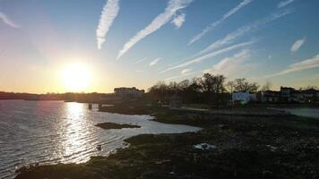 Sunset Over Waterfront with Reflections and Rocky Shoreline Near Residential Area video