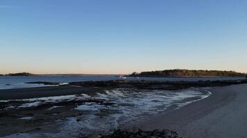 A tranquil coastal view during low tide featuring rippling sand, rocky shoreline, and clear blue sky. Ideal for nature, travel, and relaxation projects video