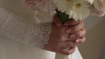 Close-Up of a Bride Holding a Bouquet of Pink and White Flowers in Lace Sleeves. Detailed shot of a bride's hands holding a delicate bouquet with pink and white flowers Perfect for wedding promotions video