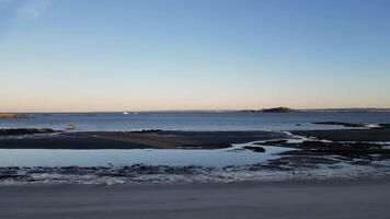 Serene Coastal Scene with Sandy Beach and Distant Island on a Clear Day video