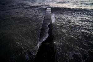 Landscape with a stone pier and raging waves in the sea. photo