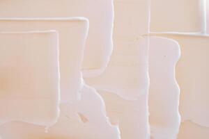 Swatch with white cream texture on a beige background. photo