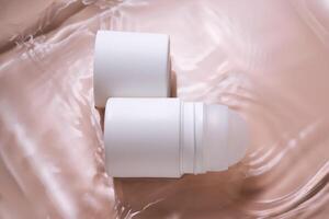 Roll-on deodorant on a pink background in water. photo