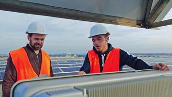 Solar generation technologies. Male workers in protective uniform provide installation of solar panels on the background of a modern electricity farm. video