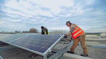 Installing of solar cells under the blue sky. Two male technicians installing photovoltaic solar cell on the background of other solar panels. video