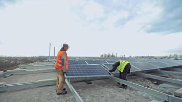 Workers install new solar panels. Two technician men installing photovoltaic panels on metal basis. Sustainable and renewable energy. video