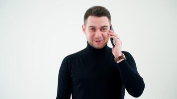 retrato do uma sorridente homem falando em a telefone. bonito homem de negocios dentro Preto suéter falando em uma Móvel telefone isolado dentro branco estúdio. video