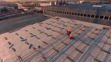 Installation solar panels on a roof. Workers put metal constructions before installing solar panels on a roof of a big building. Top view. video