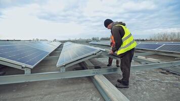 Sunny batteries installation. Workers installing solar panels on the roof of a big building. Green alternative energy. video