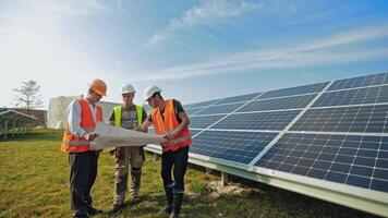 Workers studying the plan of solar panels installation. Men in protective uniform and hard hats working on a solar farm. Renewable energy. video