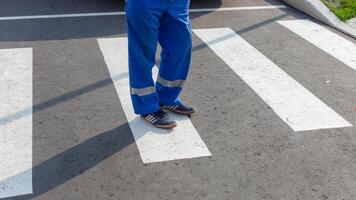 Partial view of a paramedic in uniform standing on a zebra crossing, focus on feet photo