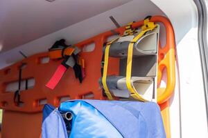 A close-up of an orange stretcher with a fixation hanging on the wall in the cabin of an ambulance photo