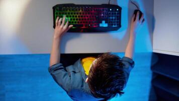 Boy plays games. Modern keyboard on the desk. Amazed boy looking up and standing. Games at home. Top view. video