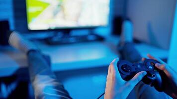 Young gamer playing game using controller. Joystick in boy's hands in front of the play station screen. Close-up. Blue light. video
