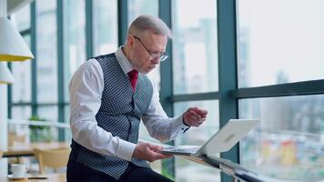 Thoughtful businessman working on computer in front of the window with city view. of working process in big company. video
