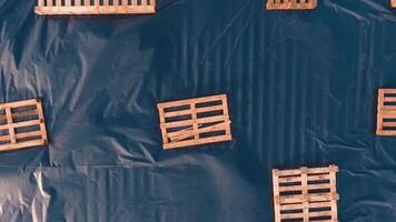 Many wooden crates on the roof of a big building. Empty wooden boxes of different sizes on the blue background. Top view. video