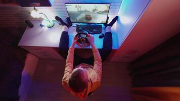 Man is playing game on computer at home. Male gamer enjoying car racing game with steering wheel. Gaming concept. Top view. video