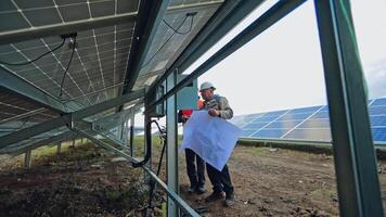 Workers installing photovoltaic panels. Technicians install the electrical system of sunny battery. View under the solar battery. video