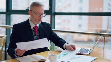 Thoughtful businessman is reading important business papers, in front of the window with city view. of business process. video