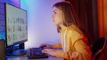 Side view of a girl working on a computer. Attractive young woman sitting in front of a monitor and looking for some information. video