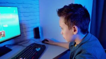 Boy playing computer game at home. Teenager sitting in front of the screen concentrated on virtual reality of the game in the room. video
