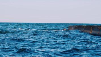 Motion of blue ocean water. Stone pier in the sea. Waves crashing on a stone dock. Nice background of blue water. Slow motion. video