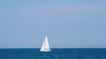 Beautiful white sail on the open sea water. Ship floating alone on the tranquil blue water under the clear sky. Slow motion. video