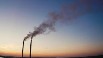 Pollution of the environment.Toxic smoke going from two pipes of a factory on the evening sky background at sunset. video