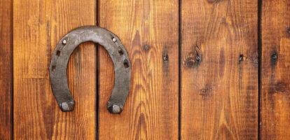 Front view of a wooden door with an iron lucky horseshoe for good luck. Concept for luck and fortune. A talisman superstition for luck. photo