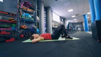 Side footage of woman doing abdominal exercise indoors. Sporty female in sportswear doing workout on the floor on a mat. video