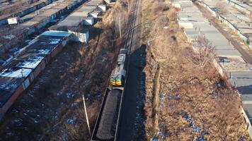 Cargo train on a railroad in sunny winter day. Top view on a freight train on the background of many garages from both sides. Aerial view. video