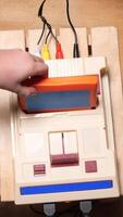 vertical Child inserting cartridge into retro game console on wooden table video