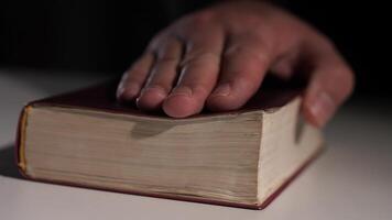 Hand resting on ancient book in low light setting video