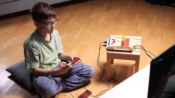 Young boy playing retro games using old console and joystick at home video