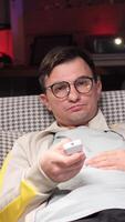 vertical Bored man watching tv and switching channels at home video