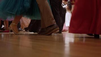 Close-up shot of partners' feet as they perform waltz steps, stepping over and balancing on their toes at the ball. Slow motion video