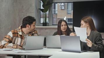 Three students are sitting at their computers in classroom, excitedly discussing project they are working on. They are reviewing documentation and planning their next steps. video