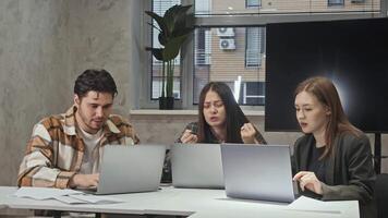 IT specialists working on application on laptops and they happy to congratulate each other on success. They rejoice and raise hands in air, shouting with joy and giving each other high fives. video
