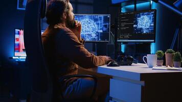 Freelancing programmer writes code on desktop PC to visualize artificial intelligence neural networks. Self employed man runs AI script on computer from apartment office, jib down shot photo