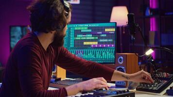 Sound engineer operates recording equipment and oversees audio performances to ensure the perfect notes. Musician composer producing sounds with MIDI controller and mixing console. Camera A. photo